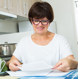 woman smiling and reading a piece of paper at a table