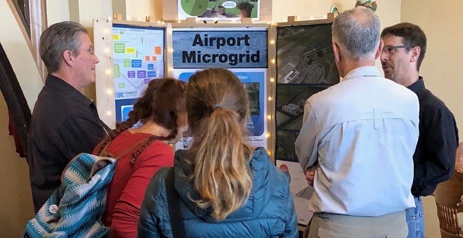 group of people gathered around a display about the airport microgrid.