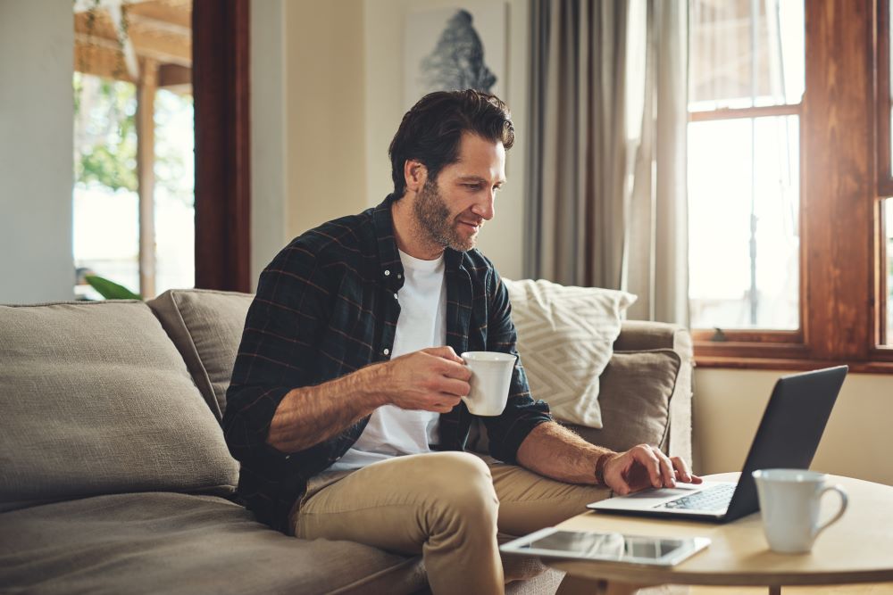 Man looking at RCEA contracting opportunities on a computer while holding a coffee cup